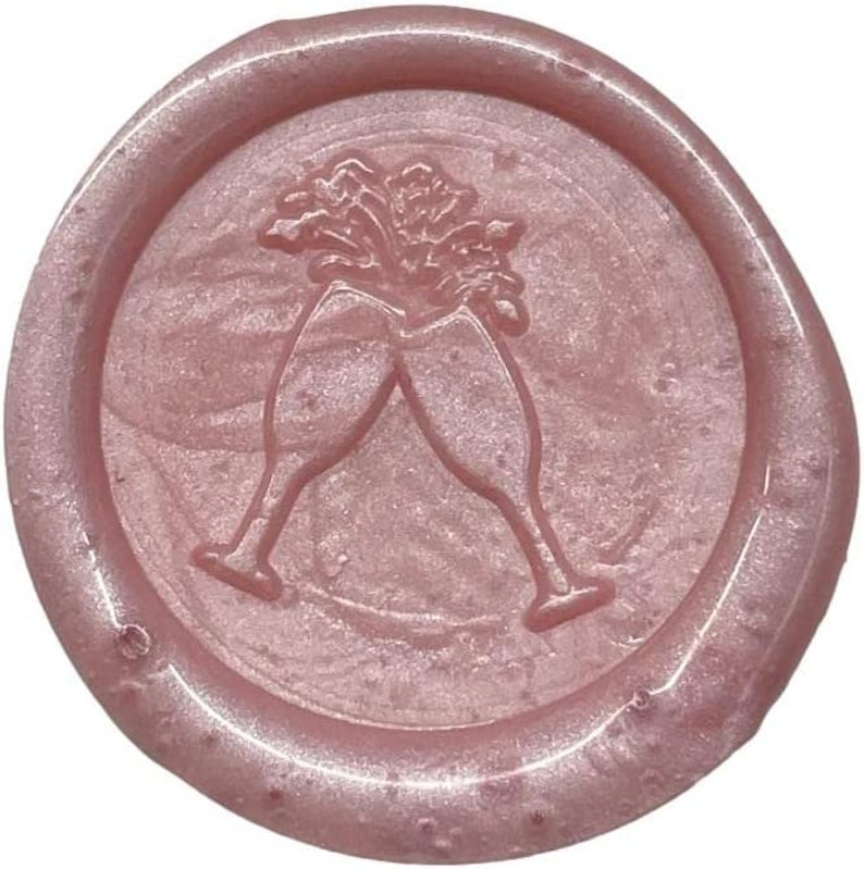 May include: A pink wax seal with a design of two champagne glasses clinking together.