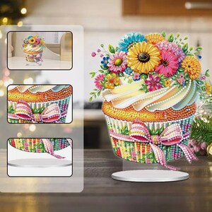 May include: A colorful diamond painting of a cupcake with a white frosting and a bouquet of flowers on top. The cupcake is on a white stand.