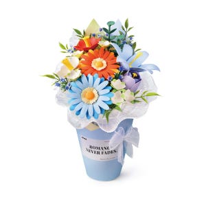 May include: A bouquet of colorful paper flowers in a light blue conical container. The arrangement includes orange, light blue, and white daisies, along with green foliage. A white ribbon is tied to the side, and the text reads ROMANCE NEVER FADES.