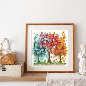 May include: A framed artwork featuring four stylized trees with colorful paper quilling flowers. The trees transition from blue to pink to red to orange, with green grass at the base. The frame is a warm brown color.