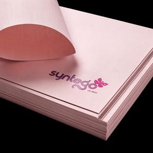May include: A stack of light pink paper sheets with a textured finish. The top sheet is curled at the corner, revealing the underside. The word syntego is printed in a dark pink font with a butterfly icon and the text Ctr. 5907 below it.