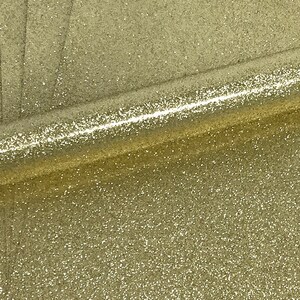 May include: A roll of gold glitter fabric with a fine, sparkly texture.