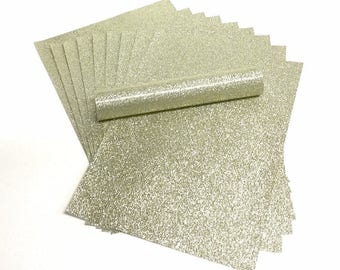 May include: A stack of sheets of gold glitter paper. The paper is textured with a fine glitter finish.