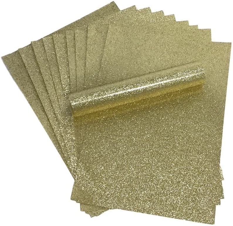 Puede incluir: Una pila de 10 hojas de papel de manualidades con purpurina dorada. El papel es de color dorado claro con un acabado de purpurina fina.