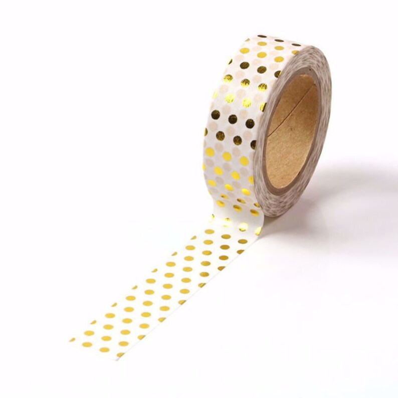 May include: A roll of white washi tape with gold foil polka dots. The tape is partially unrolled, showing the pattern.