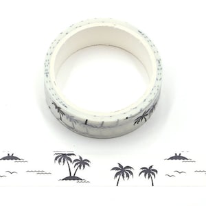 May include: A roll of white washi tape with a black palm tree and wave design. The tape is rolled up and the design is visible on the outside of the roll.