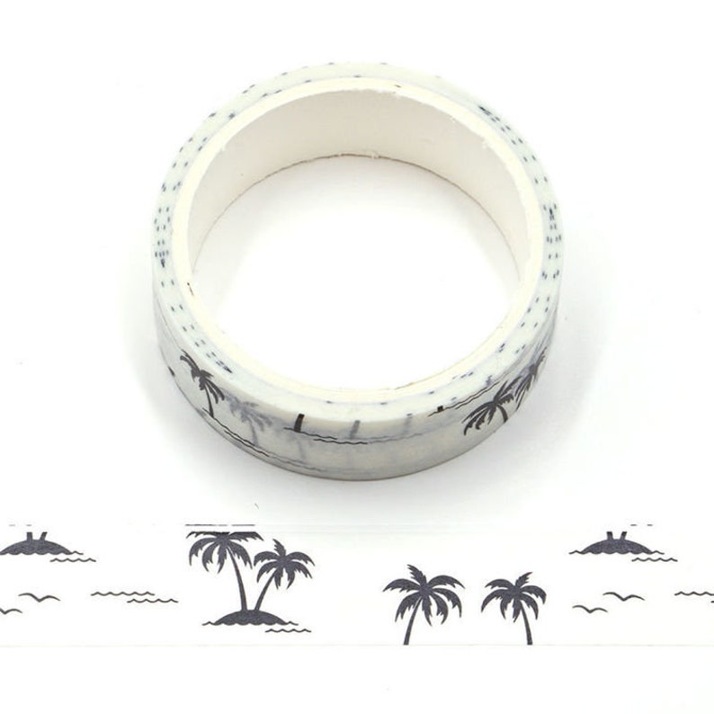May include: A roll of white washi tape with a black palm tree and wave design. The tape is rolled up and the design is visible on the outside of the roll.