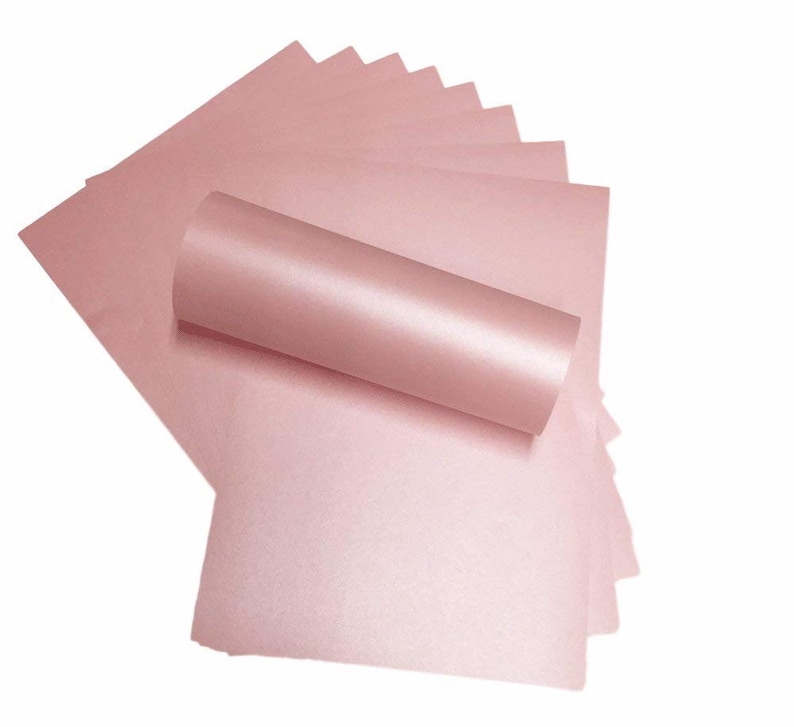 May include: A stack of 10 sheets of light pink shimmery cardstock paper. The paper is rolled up and the edges are visible.