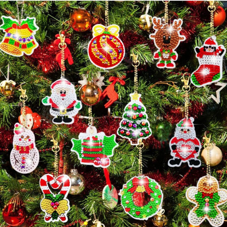May include: A collection of Christmas ornaments, including a bell, ball, reindeer, stocking, Santa Claus, snowman, holly, Christmas tree, candy cane, wreath, and gingerbread man. Each ornament is embellished with colorful gems and hangs from a gold chain.