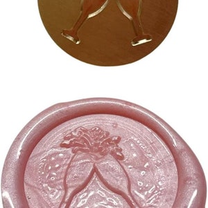 May include: A pink wax seal with a design of two champagne glasses clinking together. The glasses are filled with a bubbly liquid and there are stars around them.