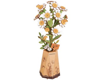 May include: A wooden model of a daisy bouquet in a tan hexagonal vase. The flowers have white petals and yellow centers, with green leaves and small bees attached. A small rectangular sign reads "for you" with a heart, and the vase is labeled "ROWOOD".