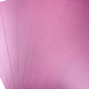 A close-up image of several pink paper sheets, likely used for various purposes such as art, crafts, or printing.