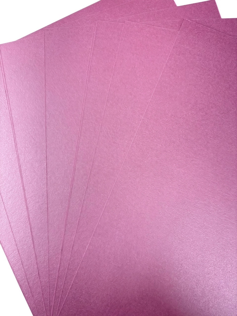 A close-up image of several pink paper sheets, likely used for various purposes such as art, crafts, or printing.