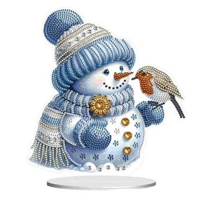 May include: A blue and white snowman with a red-breasted robin perched on its arm. The snowman is wearing a blue hat and scarf and has a carrot nose. The robin is looking at the snowman.