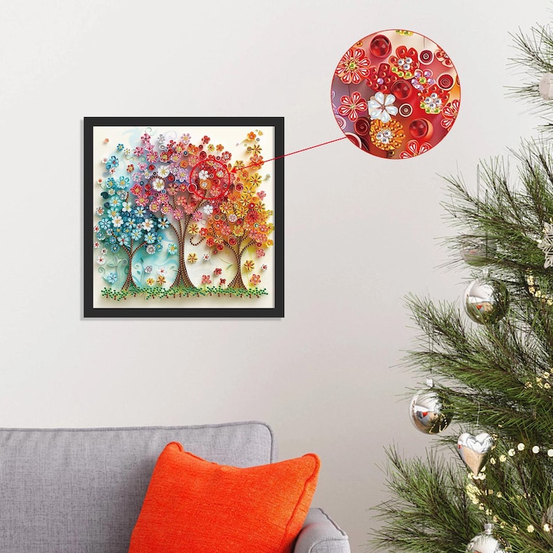 May include: A framed artwork featuring three stylized trees with colorful, paper-like flowers. The trees transition from blue to red to yellow, with intricate details and a black frame. A close-up shows the floral details.