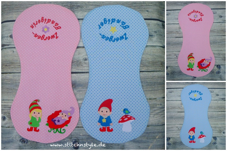 Puede incluir: Art&iacute;culos de tela rosa y azul con lunares y dise&ntilde;os de gnomos bordados. El art&iacute;culo rosa tiene un gnomo y un beb&eacute; durmiendo en un trineo rojo. El art&iacute;culo azul tiene un gnomo, una seta y un p&aacute;jaro. Texto en alem&aacute;n bordado en la parte superior.