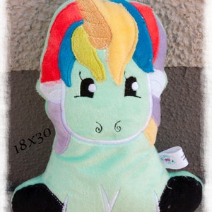 Puede incluir: Un peluche de unicornio en tonos verde menta, con una melena arco&iacute;ris y un cuerno dorado. Los textos "ITH- Einhorn" y "von Faden-Zauber" son visibles. El juguete mide 18x30 cm.