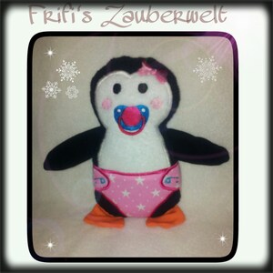 May include: A plush penguin toy with a pacifier, wearing a pink diaper with white stars. The penguin has black wings, orange feet, and a pink bow. The text "Frifi's Zauberwelt" is at the top.