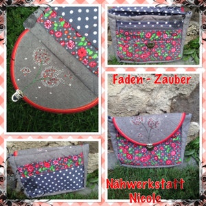 May include: A gray fabric bag with a red trim and a floral pattern. The bag has a zipper closure and a small pocket on the front. The bag is decorated with a small embroidered design of a flower with rhinestones. The text "Faden - Zauber" and "N&auml;hwerkstatt Nicole" is visible on the image.
