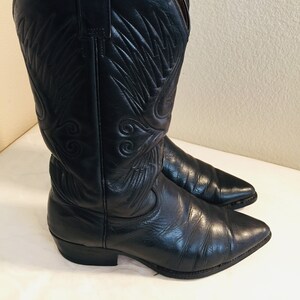 May include: A pair of black leather cowboy boots with a pointed toe and a decorative stitch pattern. The boots have a slight heel and a pull-on style.