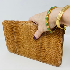 May include: A brown snakeskin clutch bag with a textured surface.
