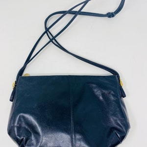 May include: A black leather shoulder bag with a gold zipper and a long strap.
