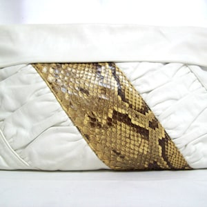 May include: A white leather clutch with a snakeskin panel. The snakeskin is a light brown color with dark brown markings.