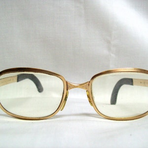 May include: Gold-tone metal eyeglasses with clear lenses and black plastic arms.