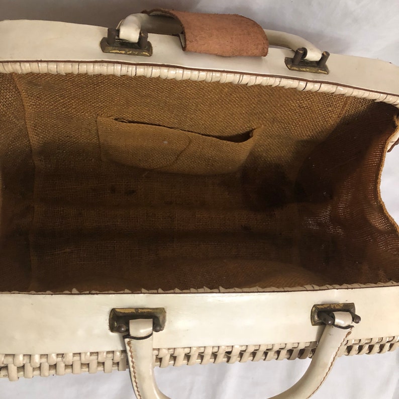 Puede incluir: Bolso de mano de cuero blanco tejido con una correa de cuero marr&oacute;n y un forro de tela marr&oacute;n. El bolso tiene un solo asa y dos cierres.