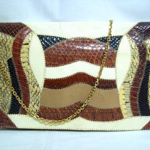 May include: A rectangular clutch with a patchwork design. The bag features a variety of earth-toned snake skin patterns, including beige, brown, and black, with a cream-colored background. A gold chain strap is attached.