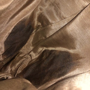 May include: Close-up of the inside of a brown fabric bag. The fabric has a subtle sheen and a fine, woven texture.