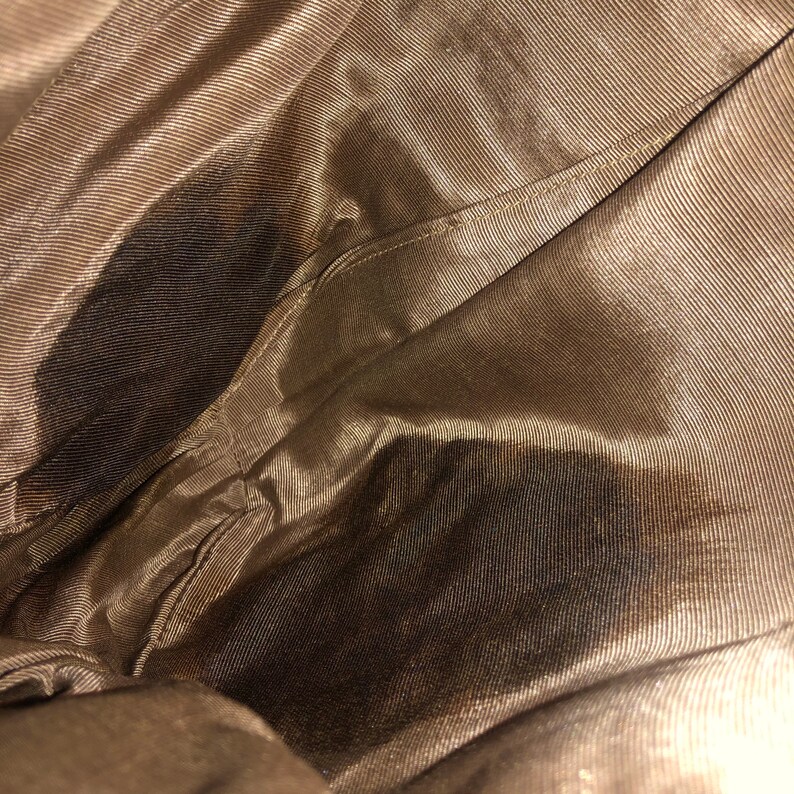 May include: Close-up of the inside of a brown fabric bag. The fabric has a subtle sheen and a fine, woven texture.