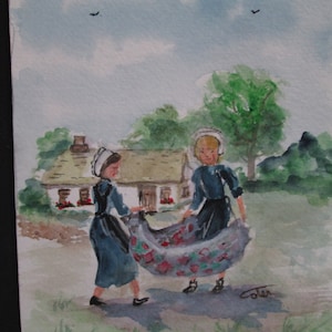 May include: Watercolor painting of two figures in traditional blue dresses and white bonnets, holding a patterned fabric. A cottage and trees are in the background under a cloudy sky. The artwork is signed by the artist.