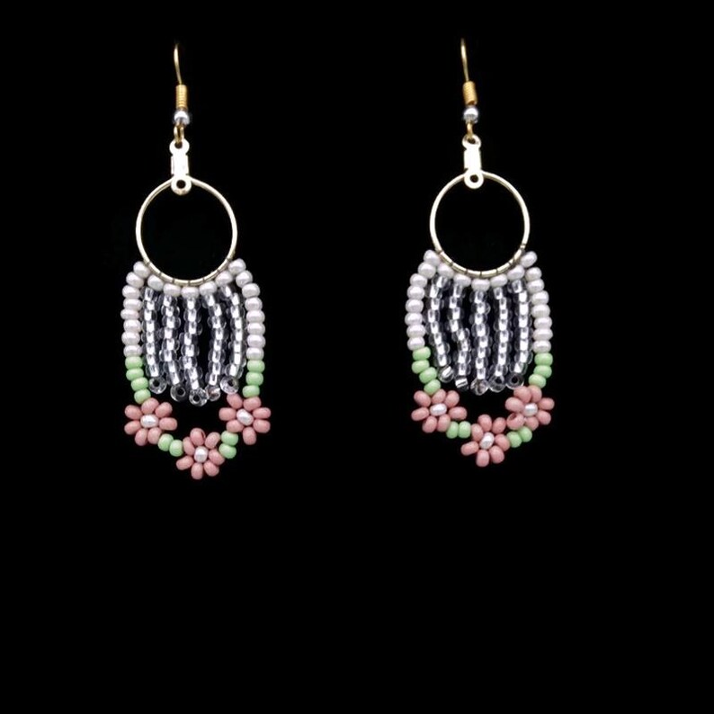 May include: A pair of dangle earrings with a silver and white beaded fringe and pink and green flower accents.