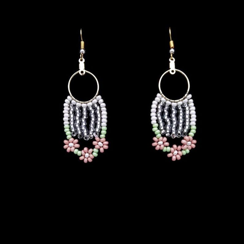 May include: A pair of dangle earrings with a silver and white beaded hoop and pink and green flower accents.