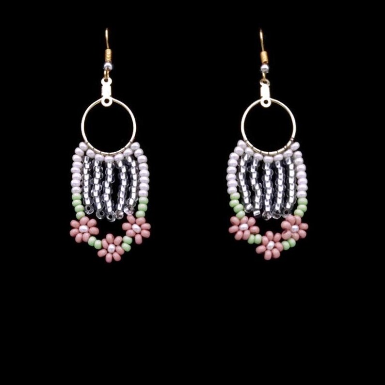 May include: A pair of dangle earrings with silver and white beads, and pink and green flower accents.