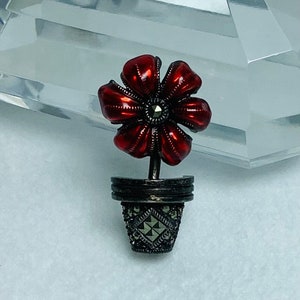 May include: A red enamel flower with a marcasite center in a silver marcasite pot.