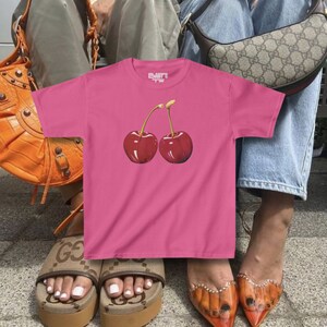 model wears awomens baby tee shirt displaying a y2k cherry
