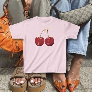 model wears awomens baby tee shirt displaying a y2k cherry