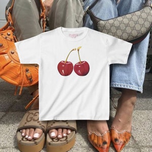 model wears awomens baby tee shirt displaying a y2k cherry