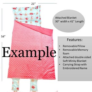 May include: A pink and blue sleeping bag with a removable pillow. The attached blanket is 30 inches wide and 41 inches long. The sleeping bag has a soft minky blanket and a carrying strap. The word "Example" is printed on the sleeping bag.