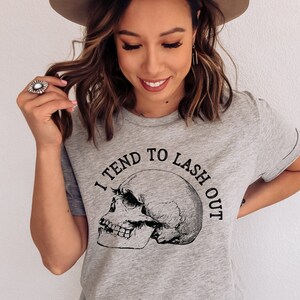May include: Gray t-shirt with a skull graphic and the text "I tend to lash out".