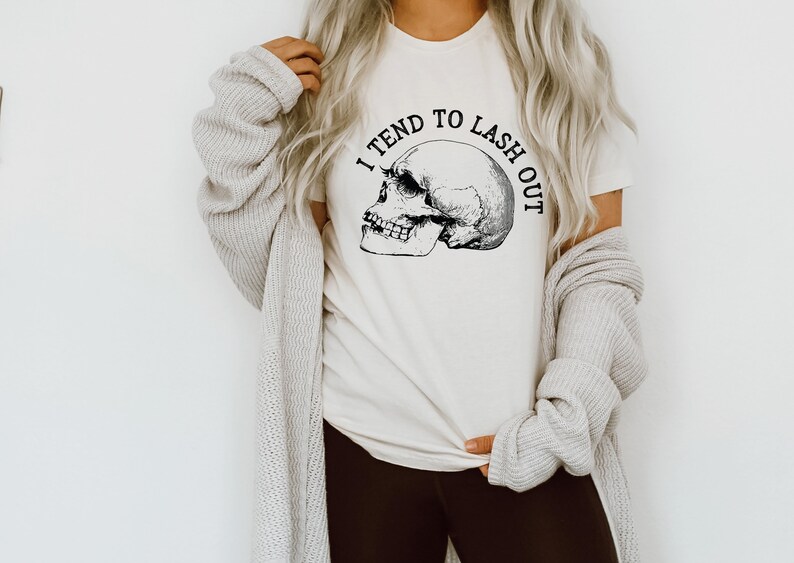 May include: White t-shirt with a black skull graphic and the text "I tend to lash out".