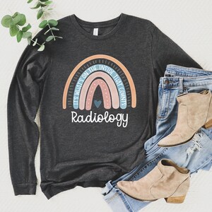 May include: A dark grey long-sleeved shirt with a rainbow graphic and the text "It's what's on the inside that counts. Radiology".