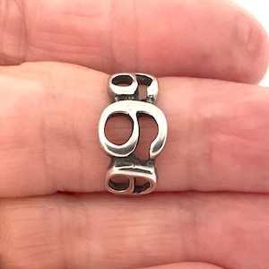 May include: A silver-coloured charm depicting the number 69. The charm is a single piece with the numbers joined. The charm is held in a hand.