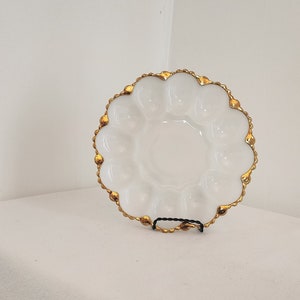 May include: White ceramic serving dish with a gold rim and scalloped edges. The dish has six indented sections.