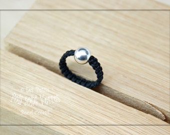 May include: A black braided ring with a silver bead. The ring is on a wooden surface. © Les Petits Pots sont Verres. Local Créatif!