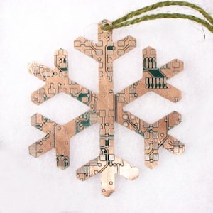 May include: A copper-coloured snowflake ornament made from recycled circuit board. The snowflake has a green circuit board pattern.