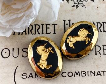 May include: Two gold-toned oval buttons with black enamel and a gold unicorn design. The buttons have a faceted, beveled edge.