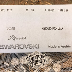 K&ouml;nnte beinhalten: Eine wei&szlig;e Schachtel mit schwarzem Text, der "ART. 1122", "47 SS", "2 GROSS SUPERIOR", "ROSE", "GOLD FOILED", "Rivoli SWAROVSKI" und "Made in Austria" lautet.